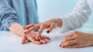 Arzt untersucht Handgelenk von Patient