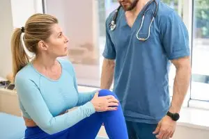 Arzt untersucht die Knieschmerzen von Patientin