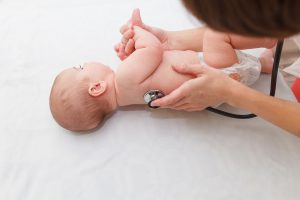 Neugeborenes wird von Arzt untersucht